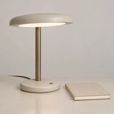 Concept desk lamp on a table beside a closed notebook.